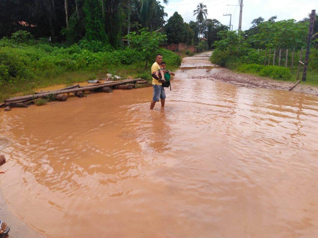 IMAGEM DO DIA – Dutra abandona Iguaíba; pai atravessa filho em lamaçal para chegar na escola